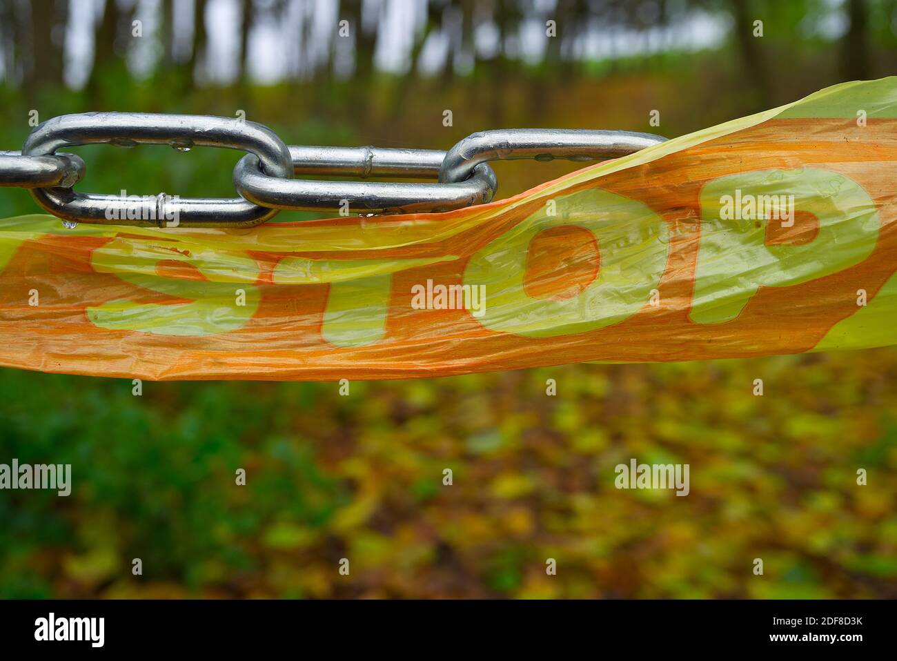 Closeup on chain barrier with stop sign on plastic tape in the woods