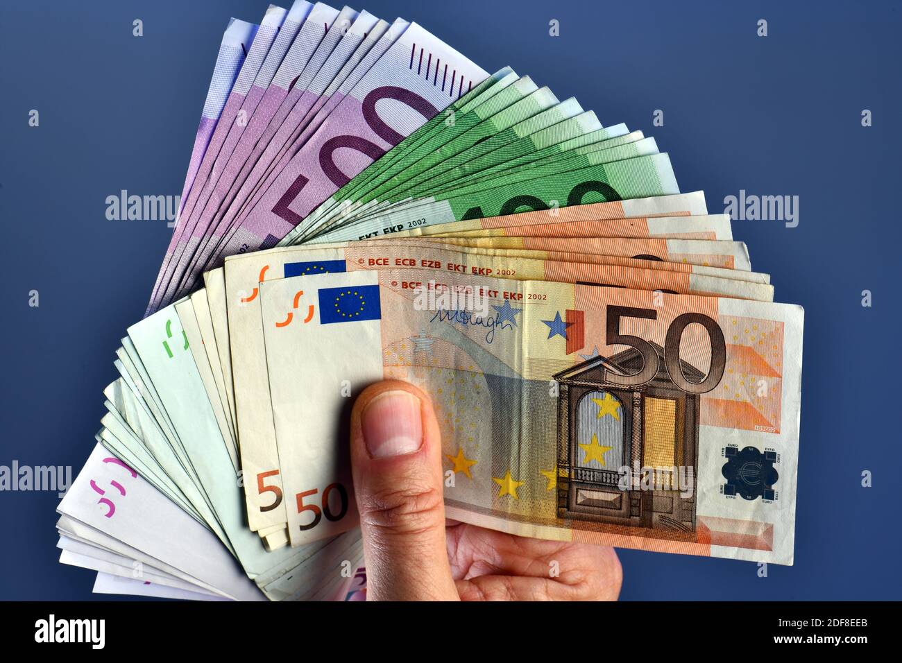 A man hand shows 20,000 Euros in 100 euro and 500 euro banknotes on a blue  background. Buy new car Stock Photo - Alamy