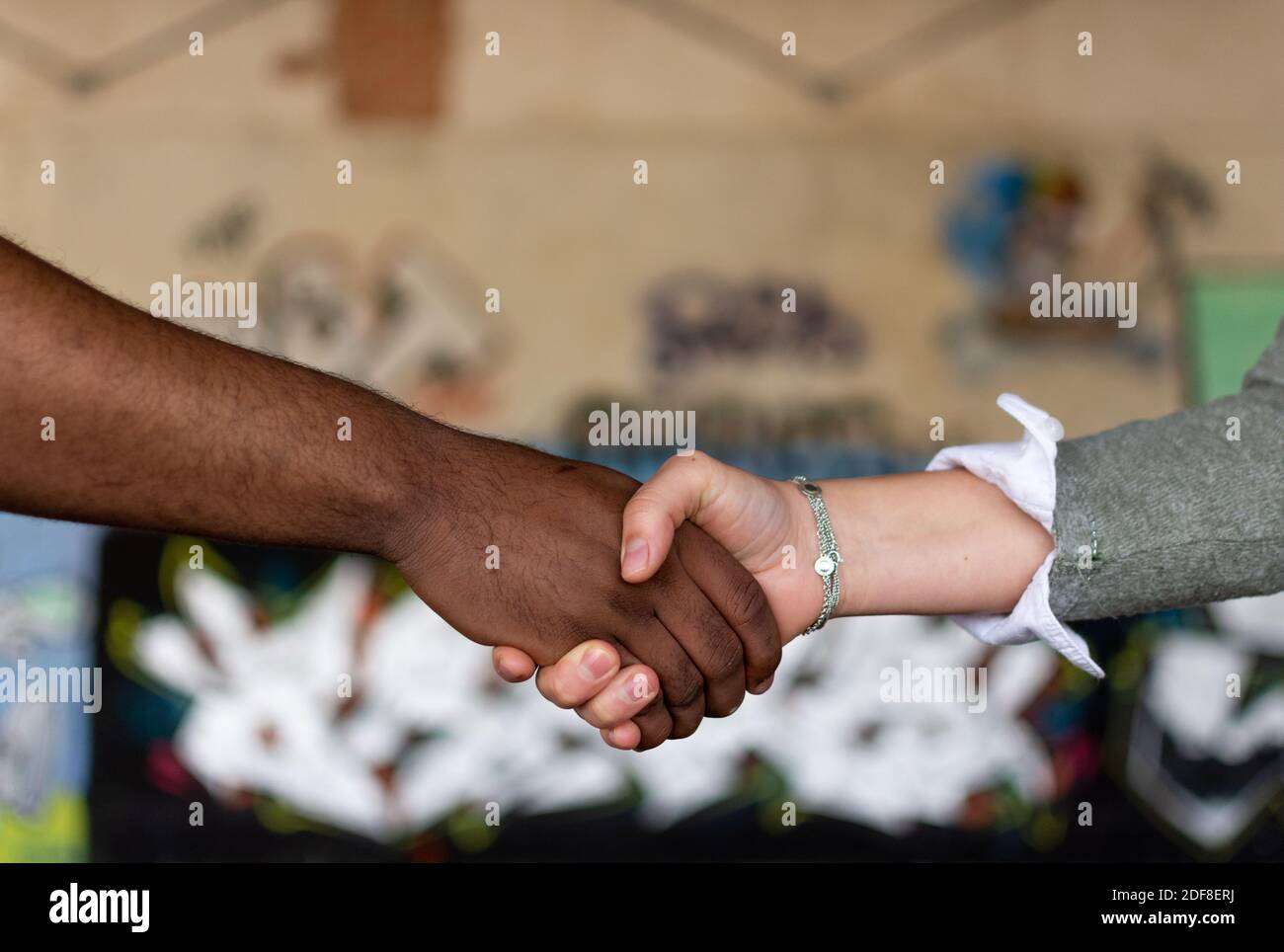 Black man and white woman holding hands. Union concept. Stop racism. Graffiti wall background. Stock Photo
