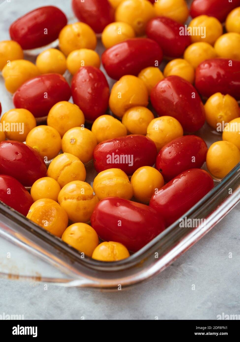 Cherry tomatoes and physalis in a baking dish before behing roasted. Stock Photo