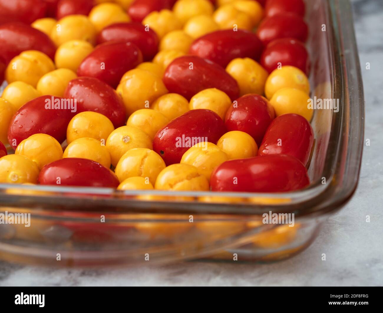 Cherry tomatoes and physalis in a baking dish before behing roasted. Stock Photo