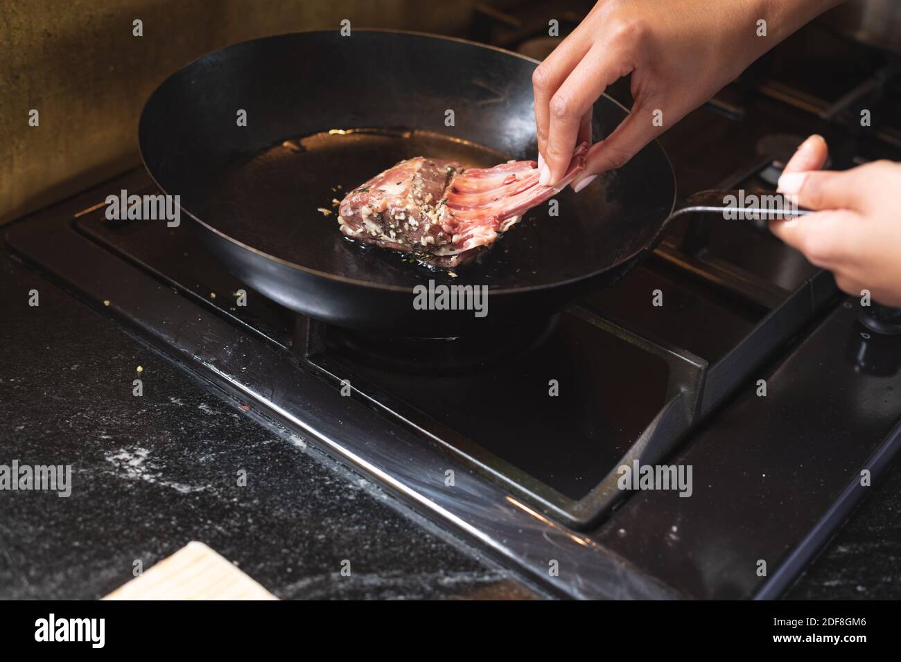 Mid section of chef putting ribs in frying pan at restaurant kitchen