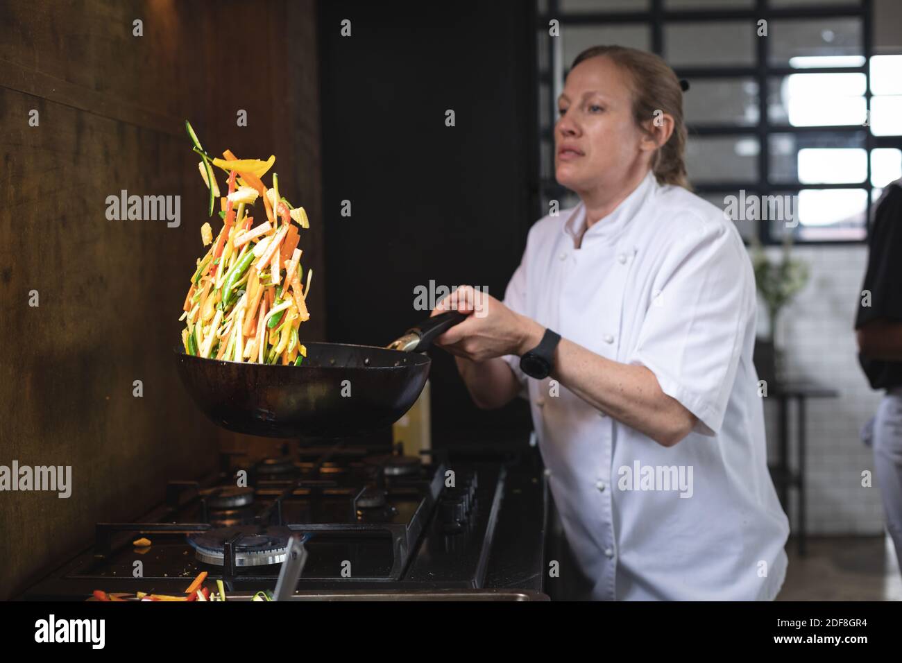 Caucasian female chef cooking in kitchen Stock Photo