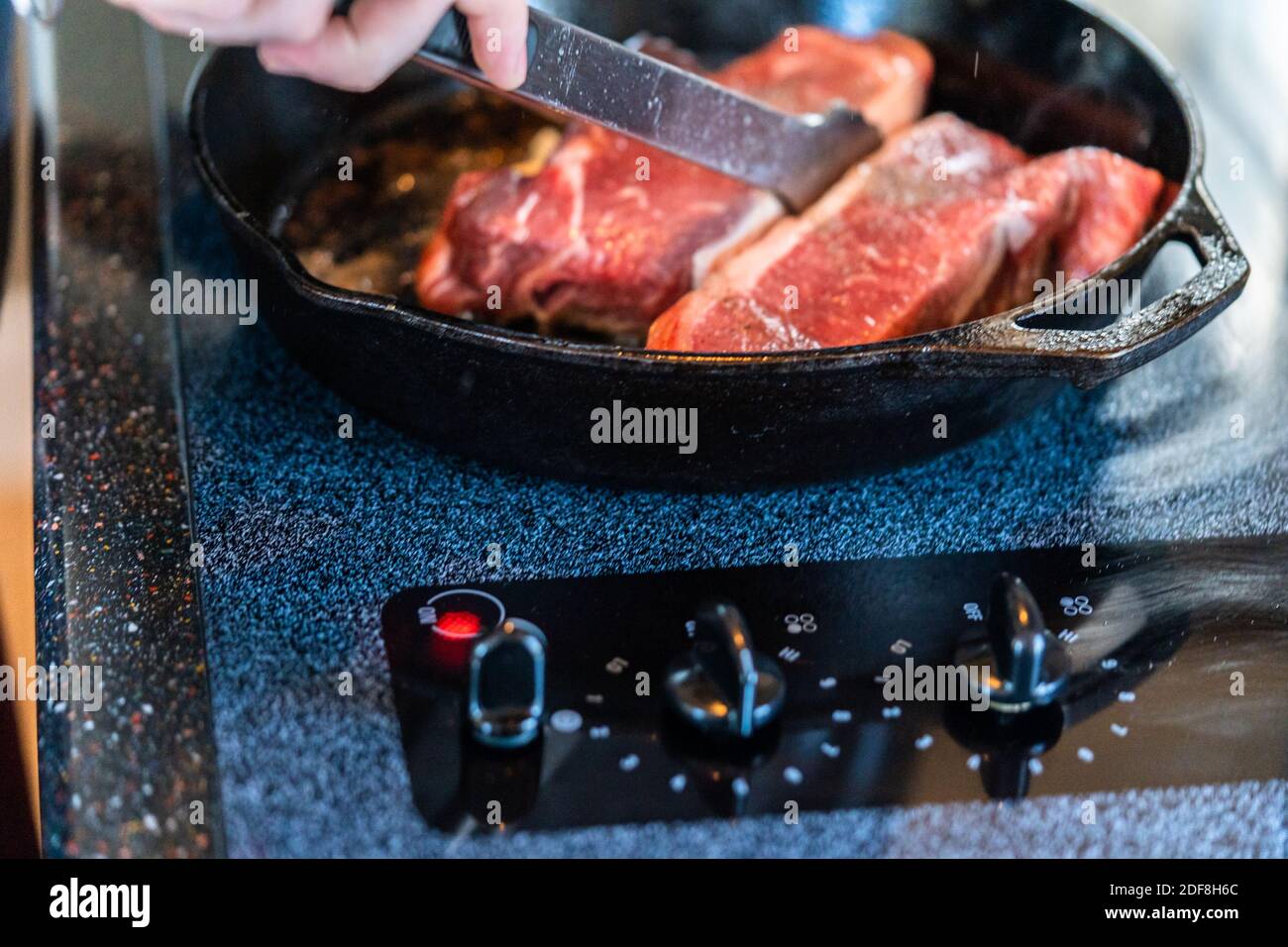 Frying New York strip steak in cast iron frying pan over the electric stove Stock Photo Alamy