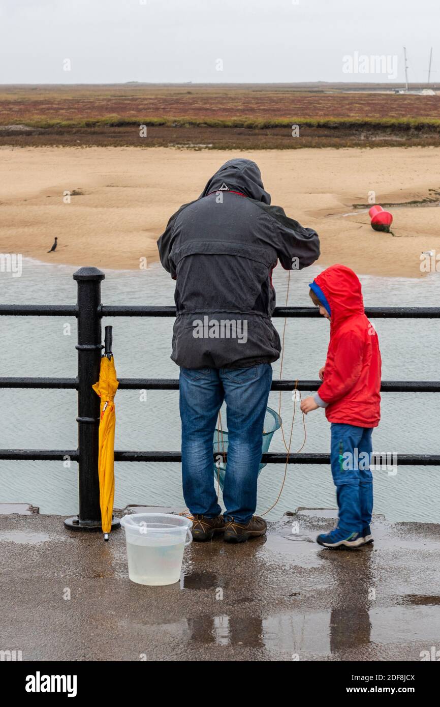 Father and son crabbing together in the rain hires stock photography