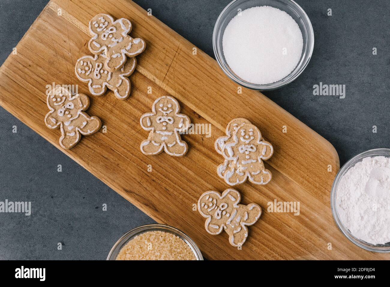 Christmas Gingerbread Man Cookies on Wooden Board With Sugar On Dark Slate Texture Stock Photo