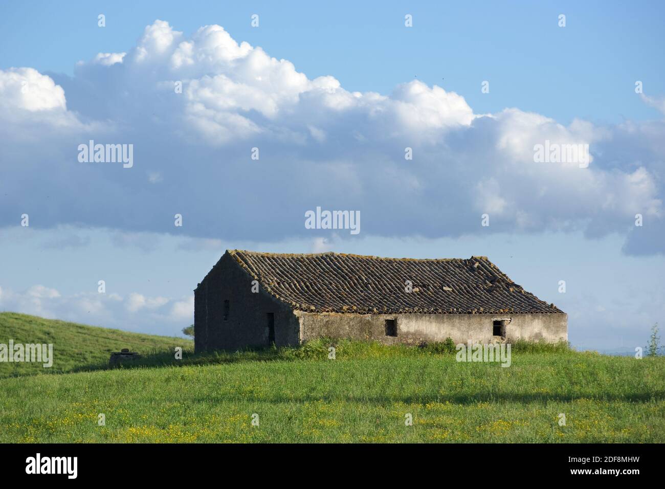 abandoned farmhouse in a grassy field and cloudy sky Stock Photo - Alamy