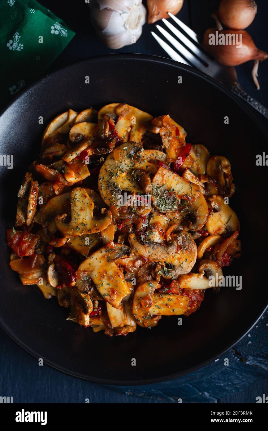 Cooked mushrooms with herbs and spices in black plate. Mushrooms saute. Stock Photo