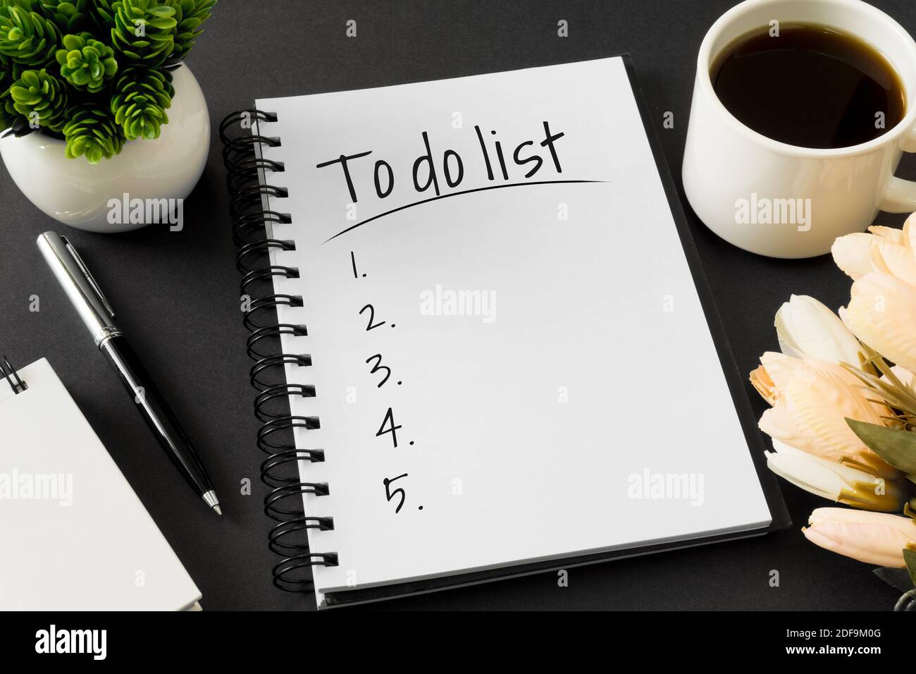 To do list. Notebook and coffee cup on black background. Stock Photo