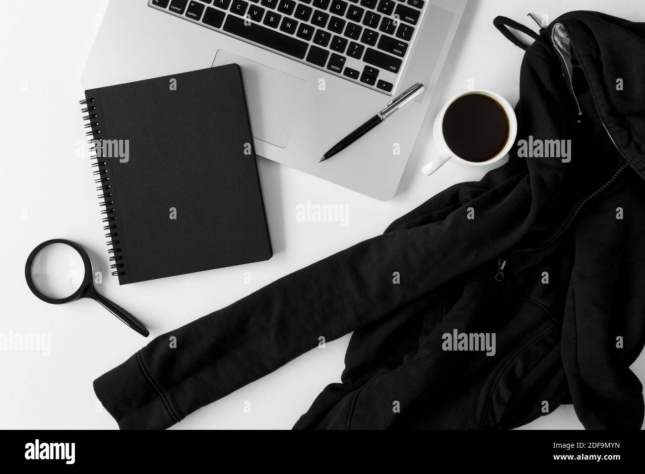 Notebook with copy space, sweater and laptop on white office table. Stock Photo