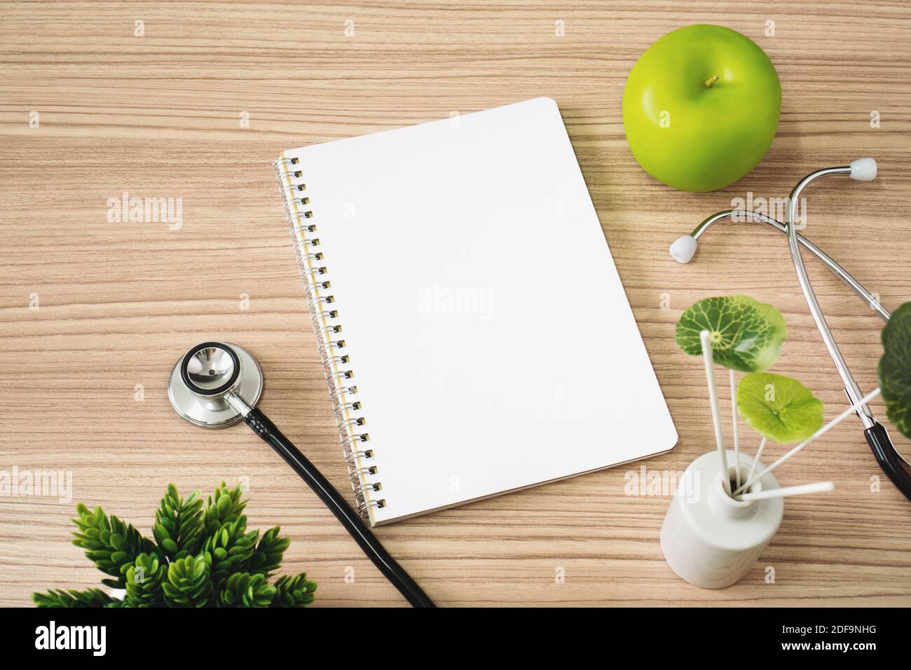 Stethoscope with notebook and apple fruits on wood background. Text copy space. Stock Photo