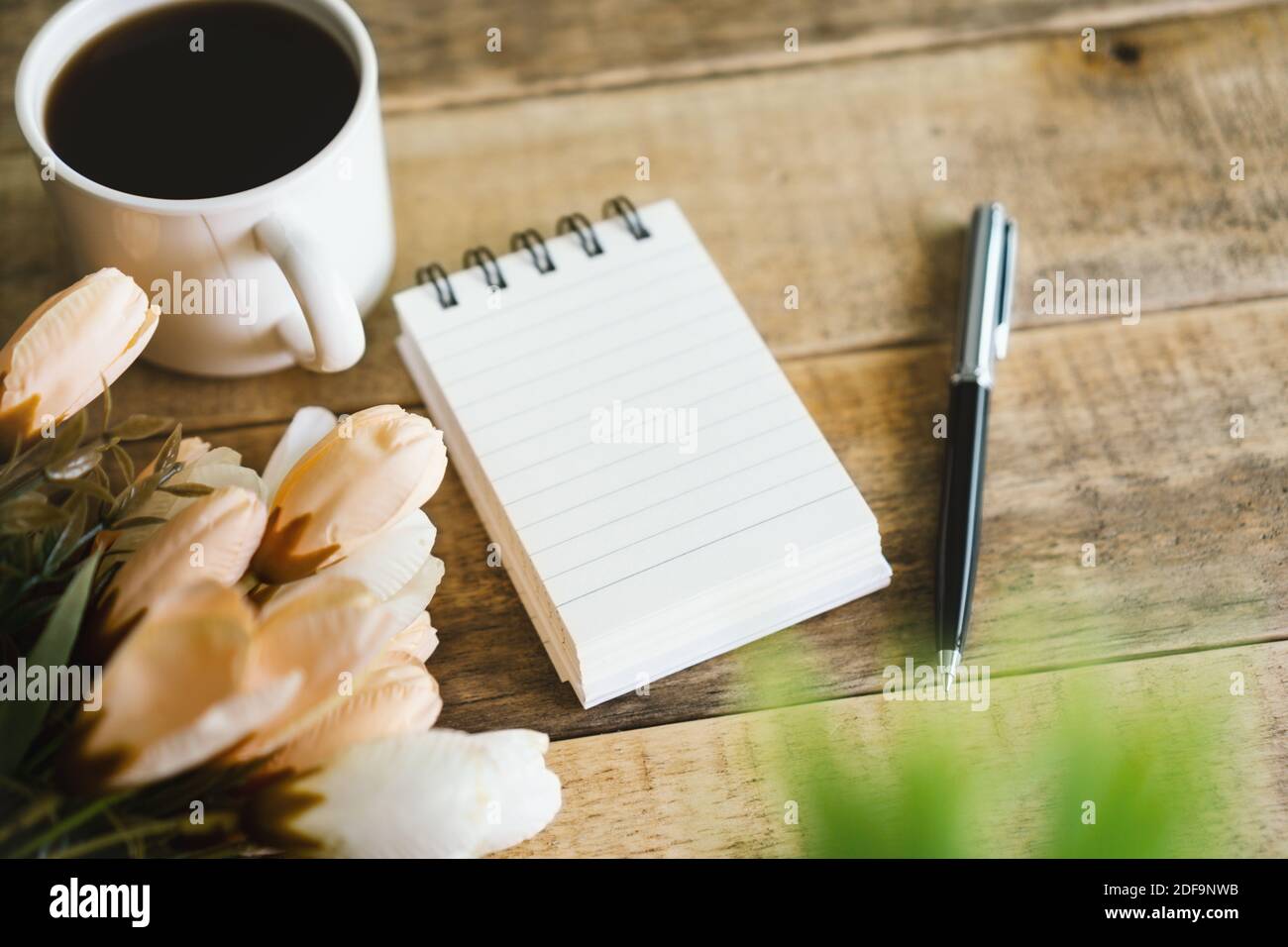 Small spiral notepad and coffee on rustic wood. Stock Photo