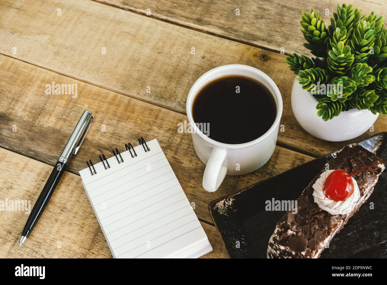 Small spiral notepad butterscotch cake and coffee on rustic wood. Stock Photo