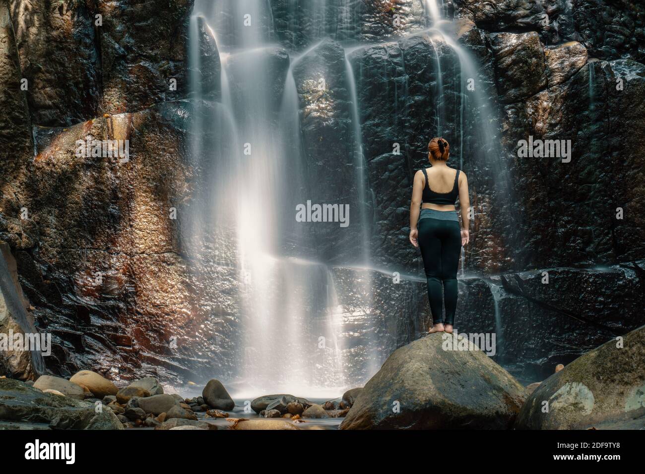 Woman standing in front of a waterfall at Kionsom Park, Sabah, Malaysia ...