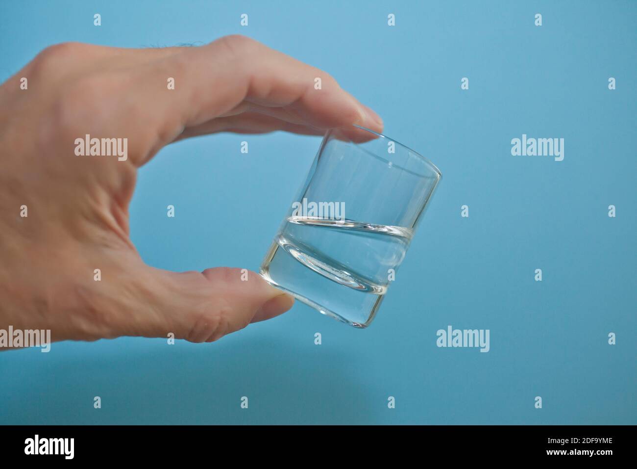 18 ml of water in small glass tumbler hand-held Stock Photo
