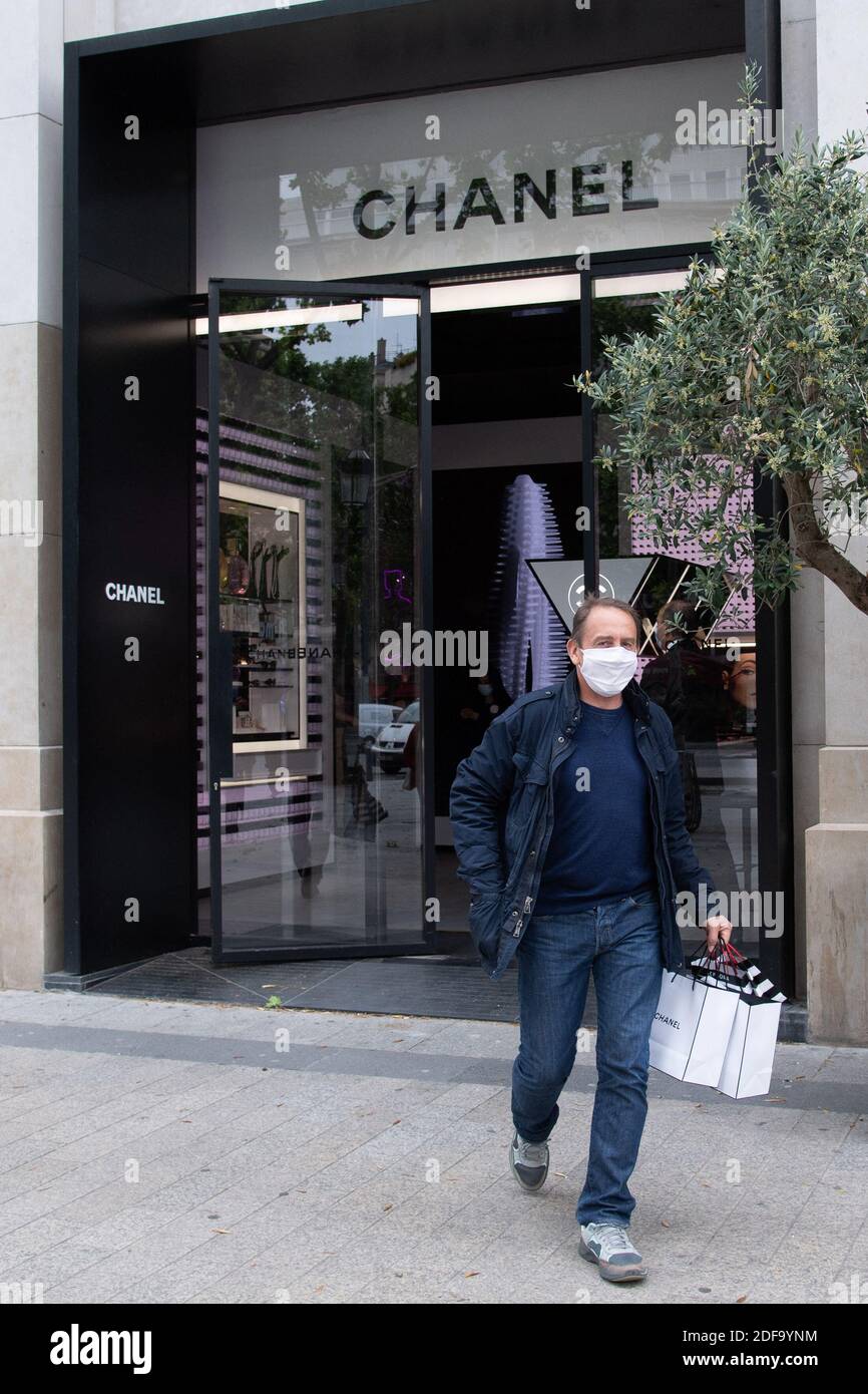 A man wearing a protective masks walks out of a Chanel store on its  reopening on the Champs Elysee avenue in Paris, France on May 11, 2020.  France began a gradual easing