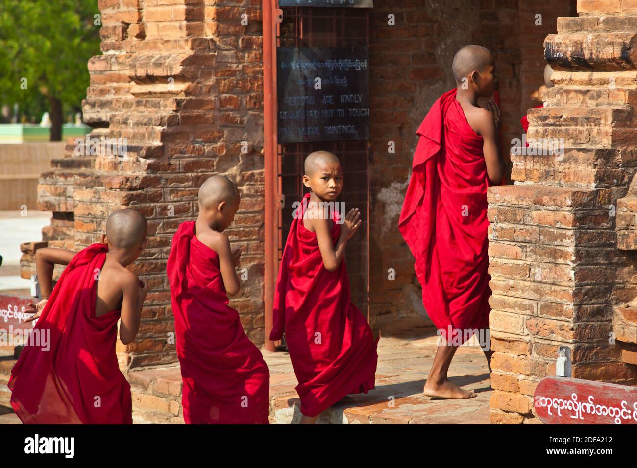 Young BUDDHIST MONKS enter one of the stupas of the ALO PYI GROUP  - BAGAN, MYANMAR Stock Photo