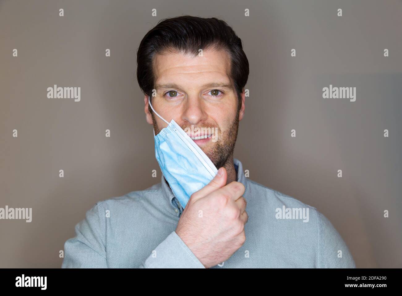 Handsome young caucasian man taking off a face mask after being cured of the Coronavirus. Stock Photo