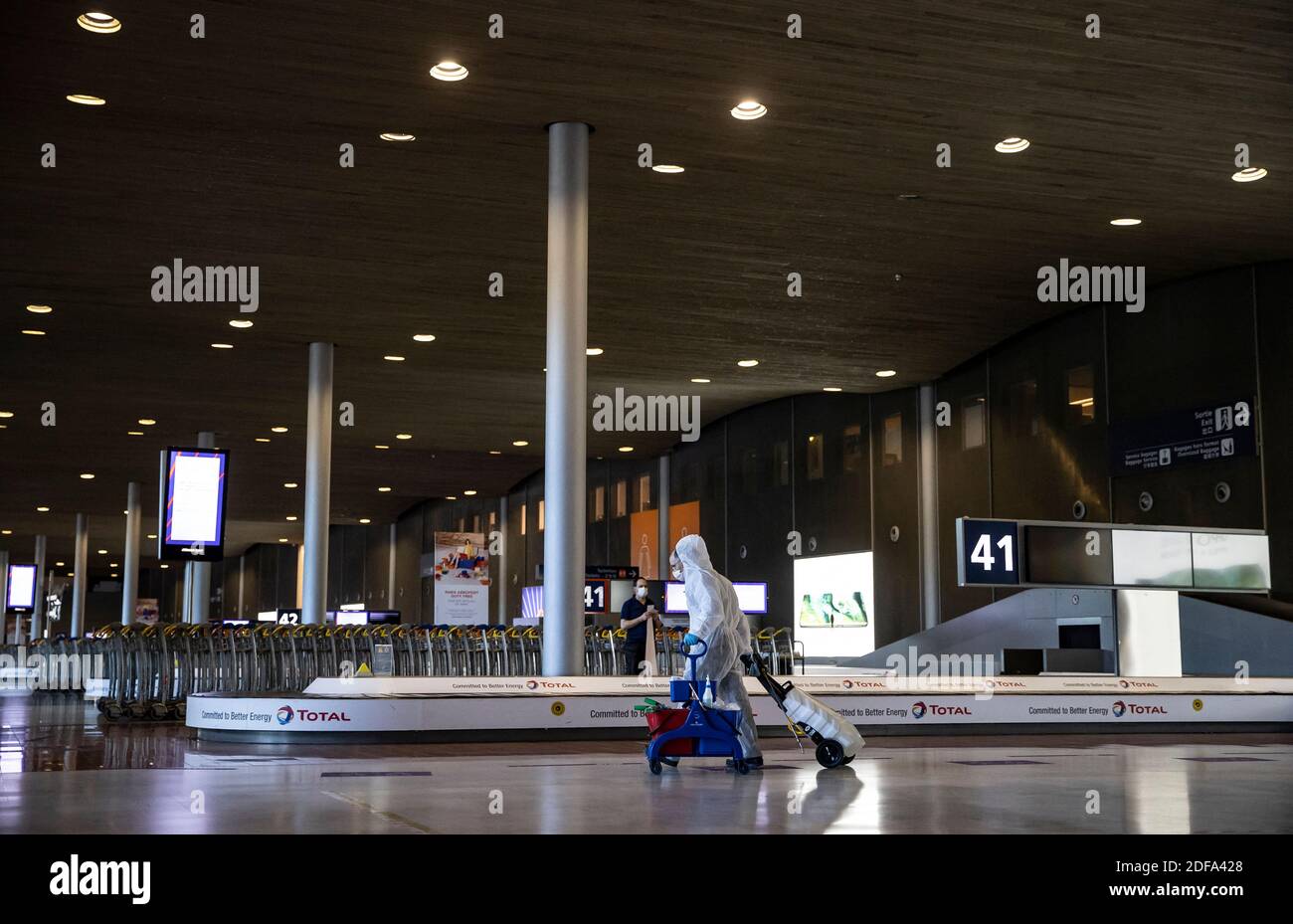 A cleaning personnel member walks in the empty baggage claim area of Terminal 2 of Charles de Gaulle international airport in Roissy near Paris France 14 May 2020. France began a gradual
