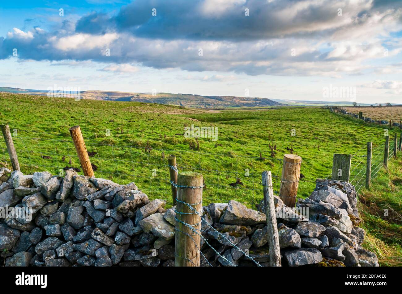 Drystone wall overlooking a field with a sinkhole or doline, in a view toward Hucklow Edge on Bradwell Moor near Castleton, Derbyshire. Stock Photo