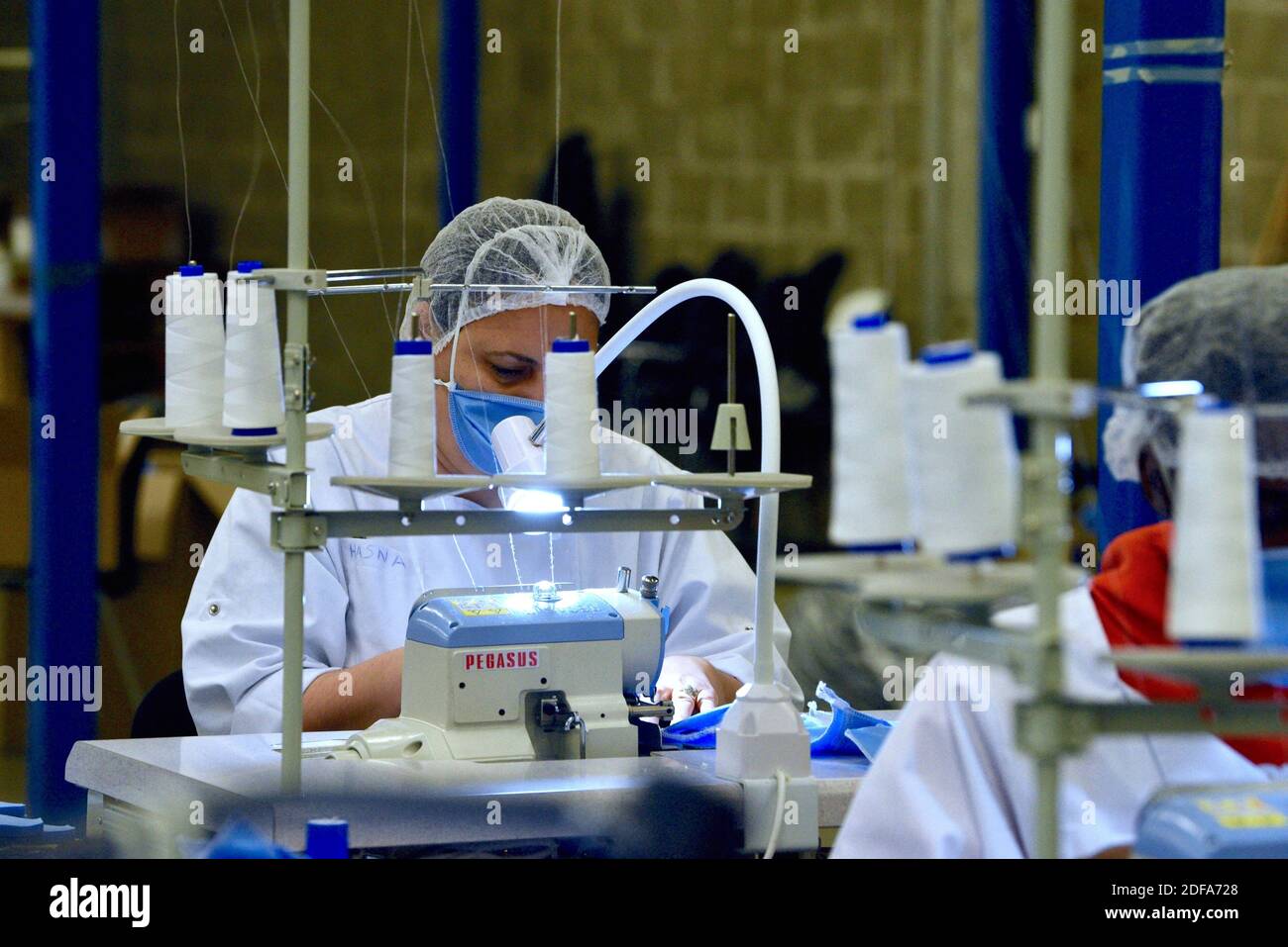 During the coronavirus crisis - covid 19, the company Presta Terre, specialized in activity and social integration, manufactures washable fabric masks and packages hydro alcoholic gel. Luc De Gardelle (white pullover), manager, says his company has recruited staff to be able to manufacture 150,000 masks per week. It also packages 50,000 litres of hydro-alcoholic gel for the Departmental Council of Bas Rhin 67. It continues its activity every day, until the end of the orders and this crisis. Assina professional seamstress (yellow sweater) and Patrycja team leader (white blouse) explains the pro Stock Photo