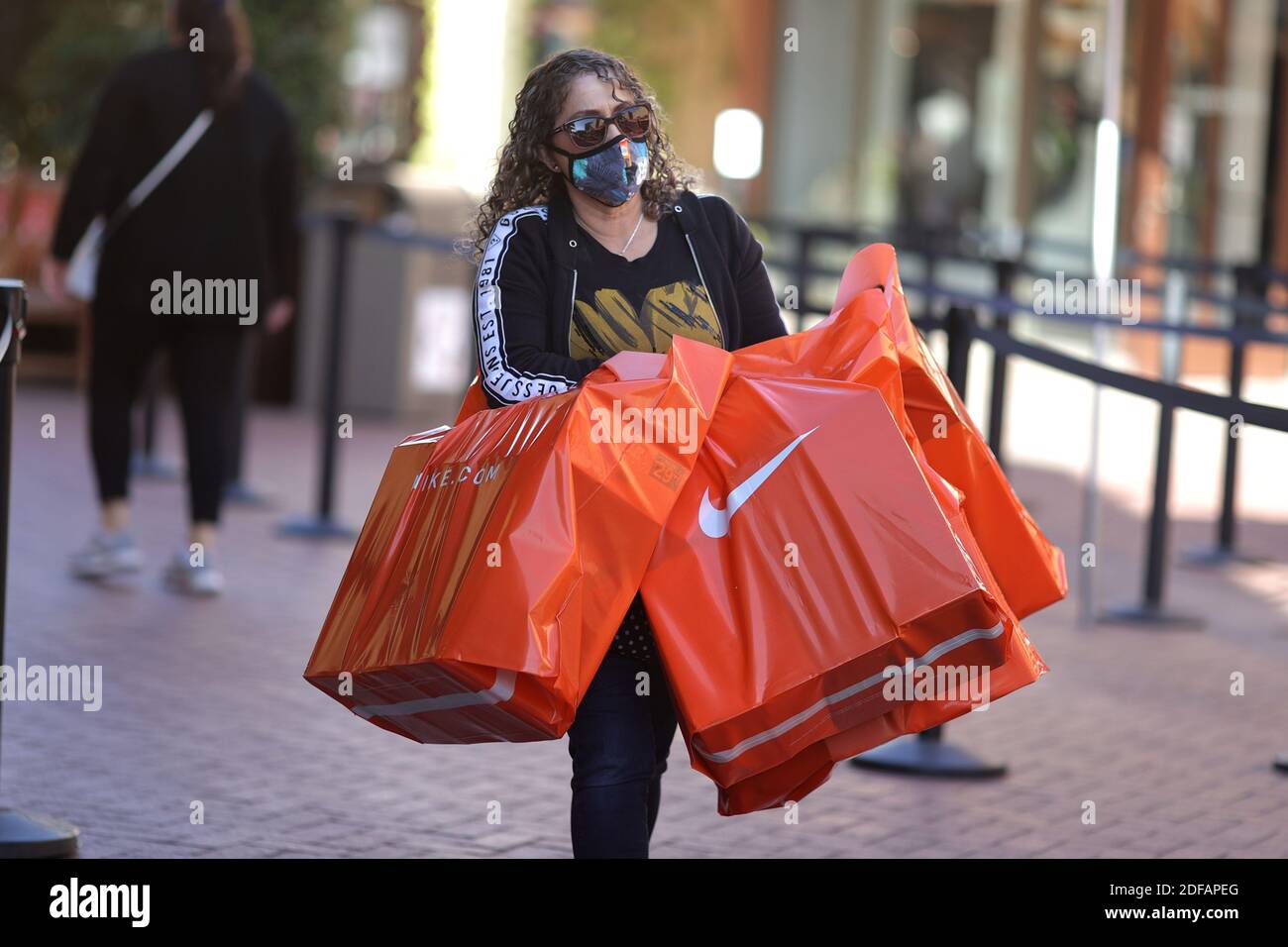 A woman carries Nike shopping bags at the Citadel Outlet mall, as the  global outbreak of