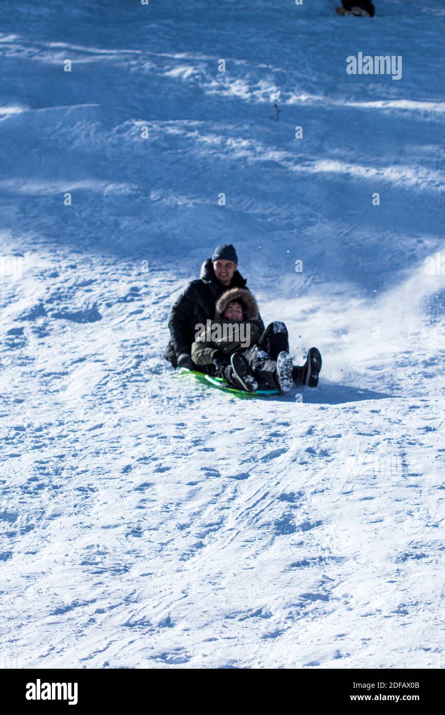 Boys Sledding on a Snowy Mountain Hill Stock Photo