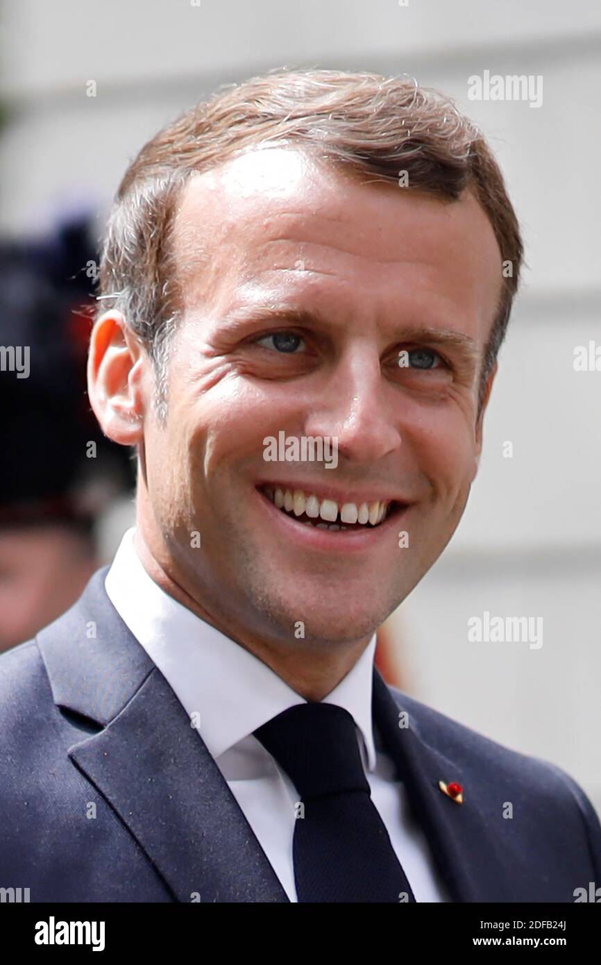 French President Emmanuel Macron smiles as he arrives to lay a wreath