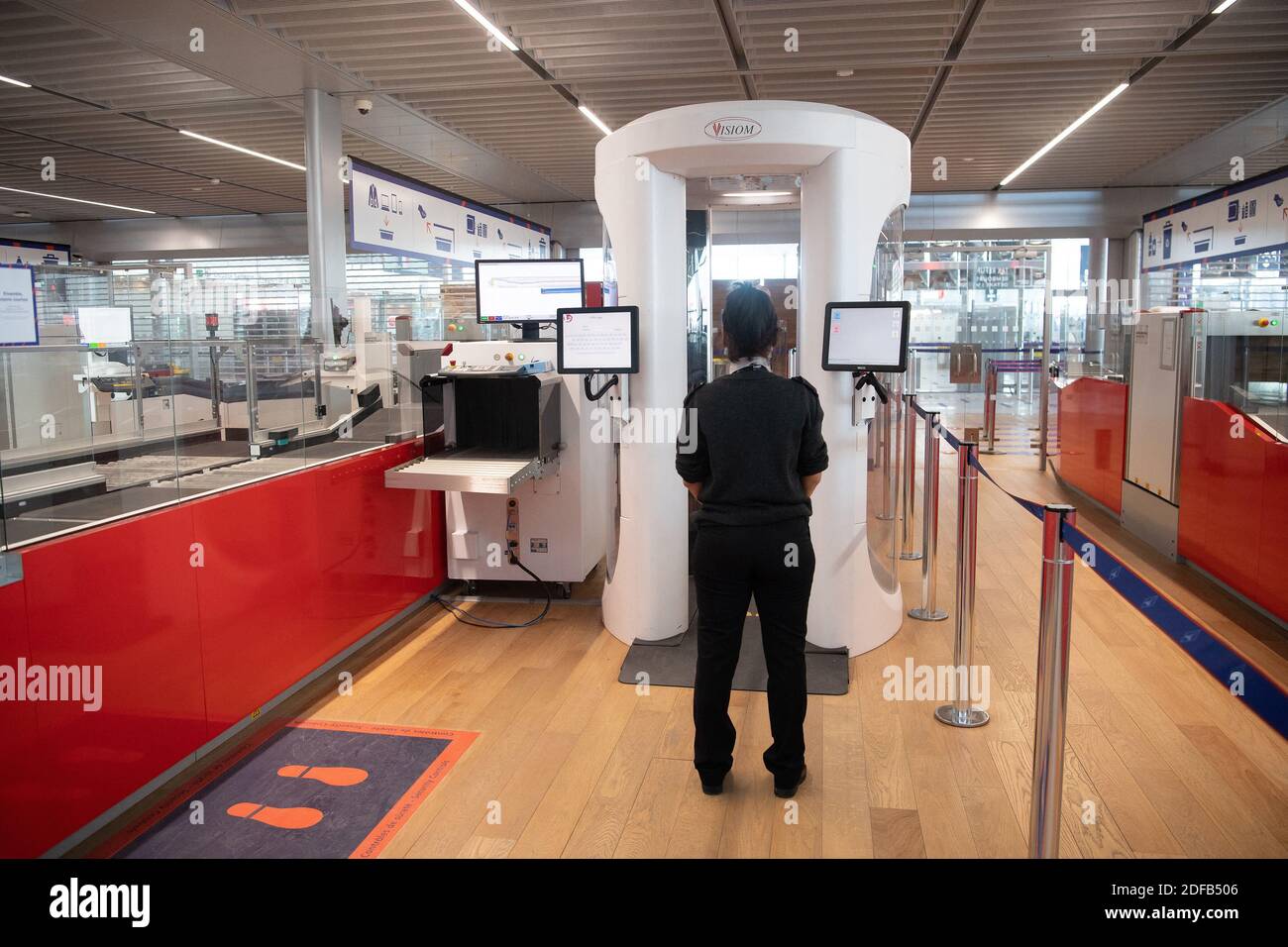 An airport staff member wearing protective face mask stands next to a body  scanner in the boarding area of the Terminal 3 at the Orly airport, in Orly  on the outskirts of