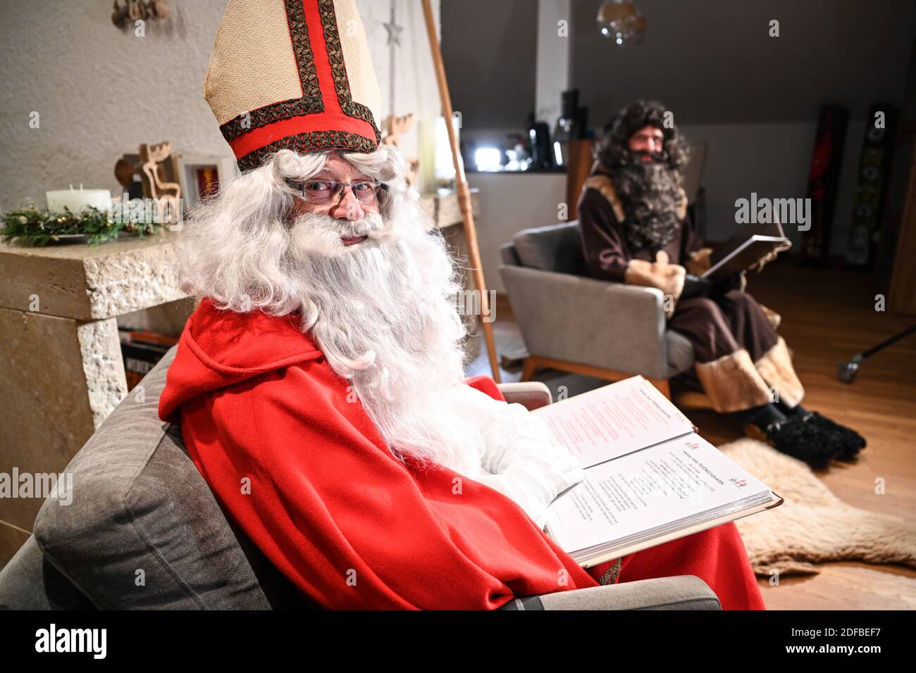 Friedrichshafen, Germany. 01st Dec, 2020. Berthold Erich Schwarz (l) as Bishop Nikolaus and Michael Huber as servant Rupprecht are sitting in front of the fireplace in two armchairs to record a video message to the families and children. (to dpa: 'Nicholas in pandemic mode - online message for families') Credit: Felix Kästle/dpa/Alamy Live News Stock Photo