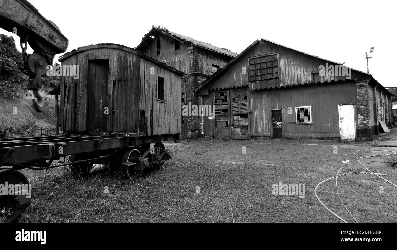 Old rotten and rusty abandoned waggon standing next to an abandoned shed [Black and White] Stock Photo