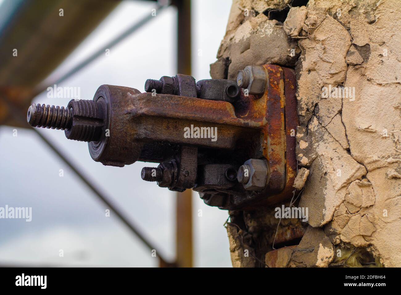 A rusty bolt sticks out in a concrete wall is falling apart Stock Photo