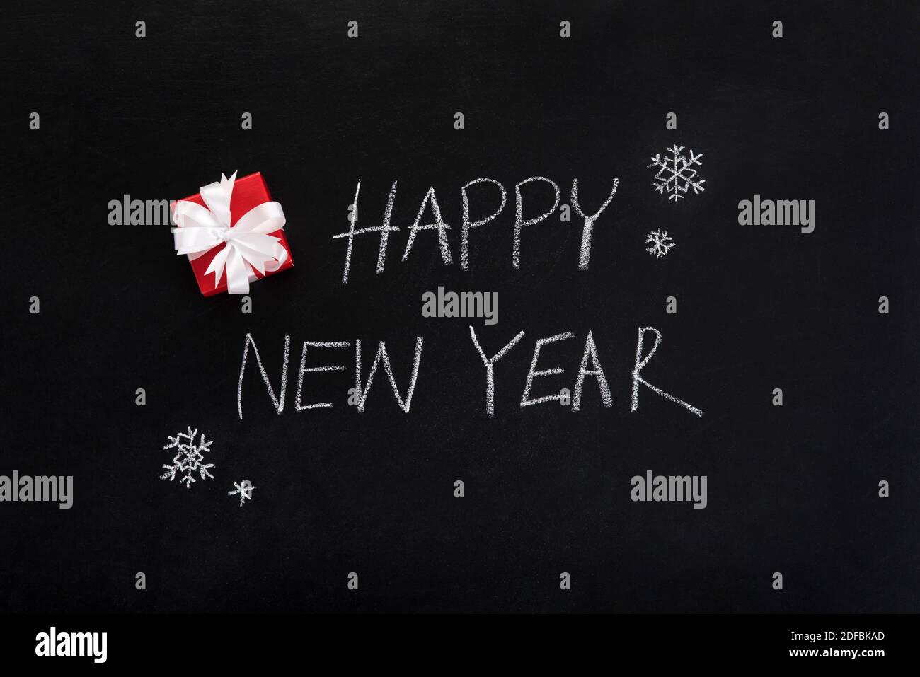 HAPPY NEW YEAR text , handwriting, on blackboard with small red gift box - top view Stock Photo