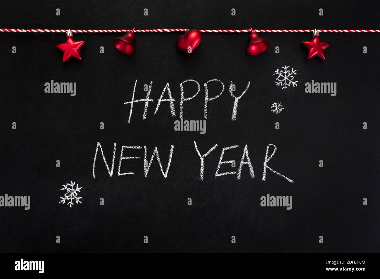 HAPPY NEW YEAR text with decorated items on blackboard Stock Photo
