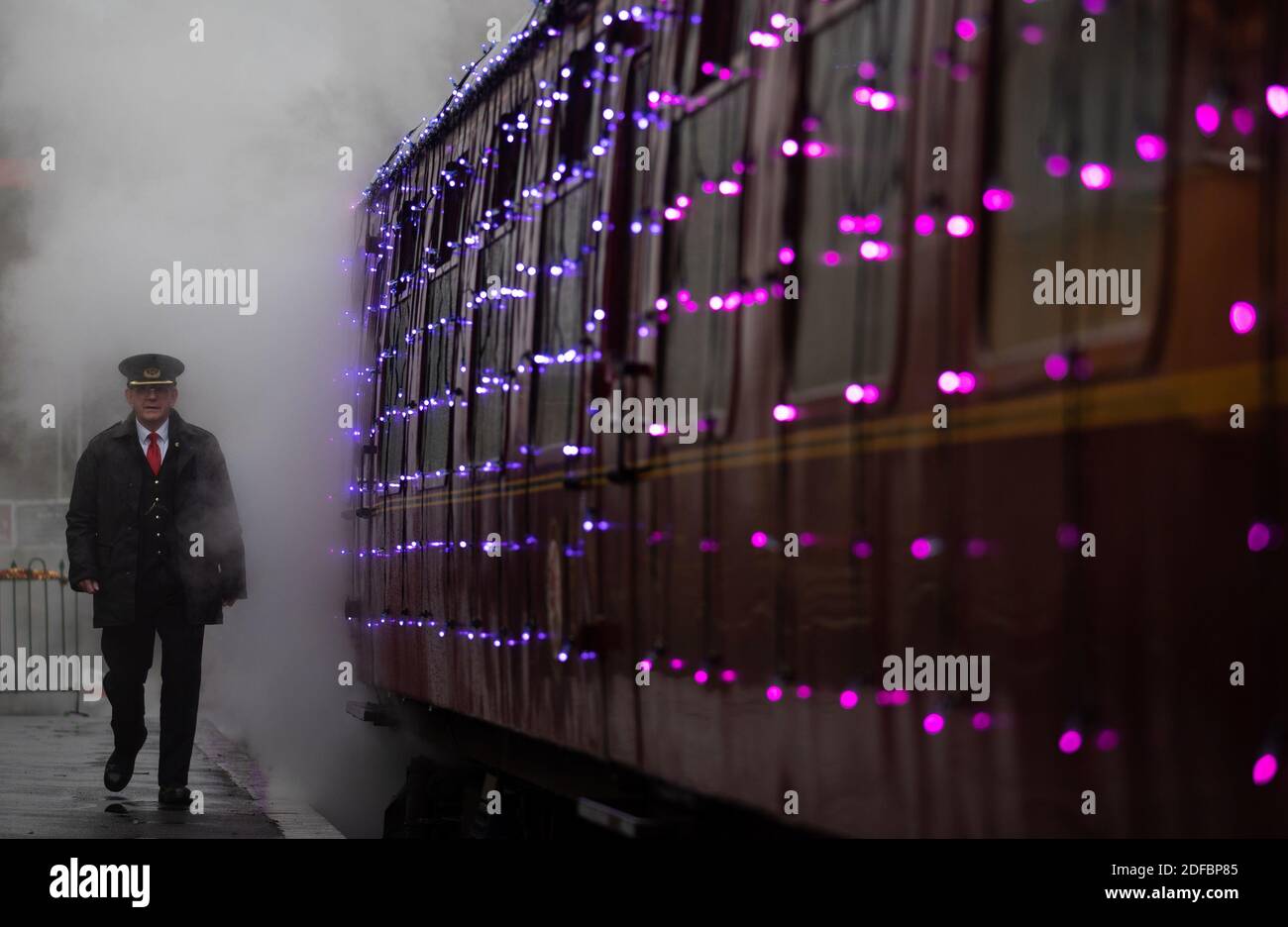 A guard walks past the world's first digital LED train, created using thousands of fully controllable colour mixing LED lights, at Alresford Station in Hampshire during a preview of Steam Illuminations at Watercress Line, which opens to the public on Friday December 4. Stock Photo