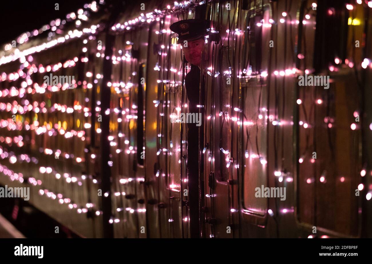 A guard looks out of a window from the world's first digital LED train, created using thousands of fully controllable colour mixing LED lights, whilst at Alton station during a preview of Steam Illuminations at Watercress Line, which opens to the public on Friday December 4. Stock Photo