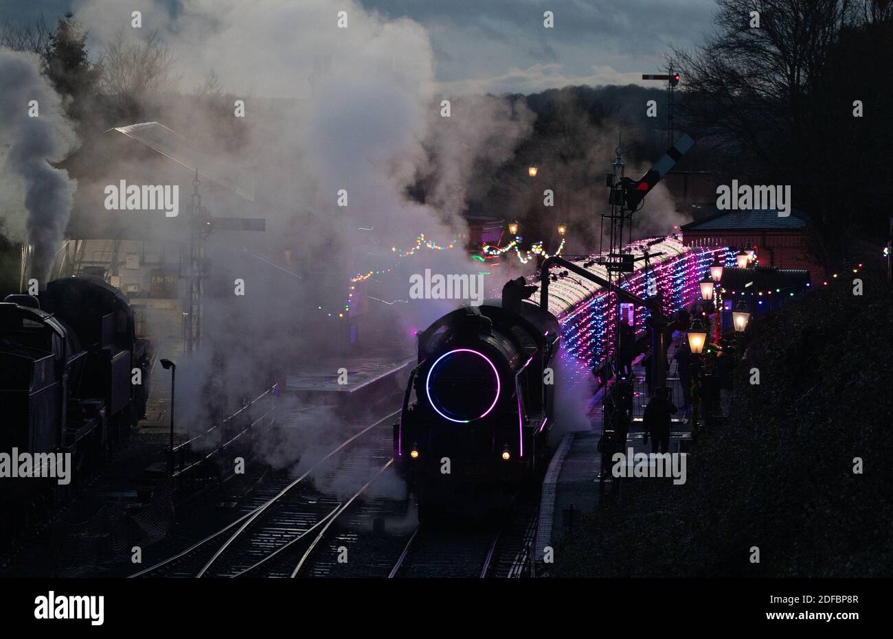 The S15 class steam locomotive 506 takes on water at Ropley station as it pulls the world's first digital LED train, created using thousands of fully controllable colour mixing LED lights, during a preview of Steam Illuminations at Watercress Line, which opens to the public on Friday December 4. Stock Photo