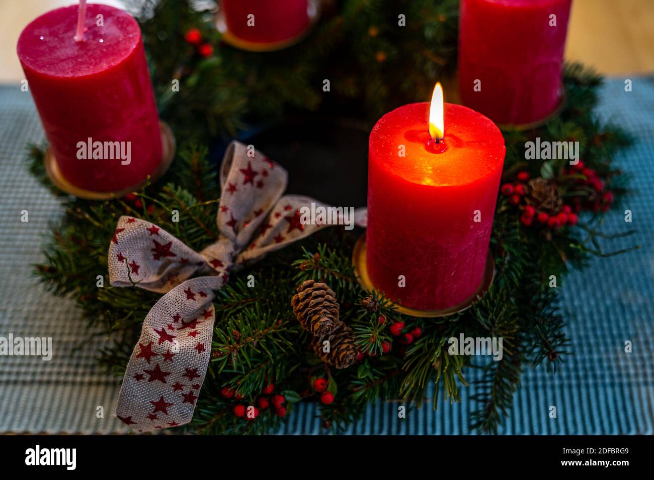 Adventskranz, erster Advent, brennende Kerze, Tannenkranz mit Schlaufe, Fichtenzweig, Lärchenzapfen, rote Beeren, first advent,  advent wreath Stock Photo
