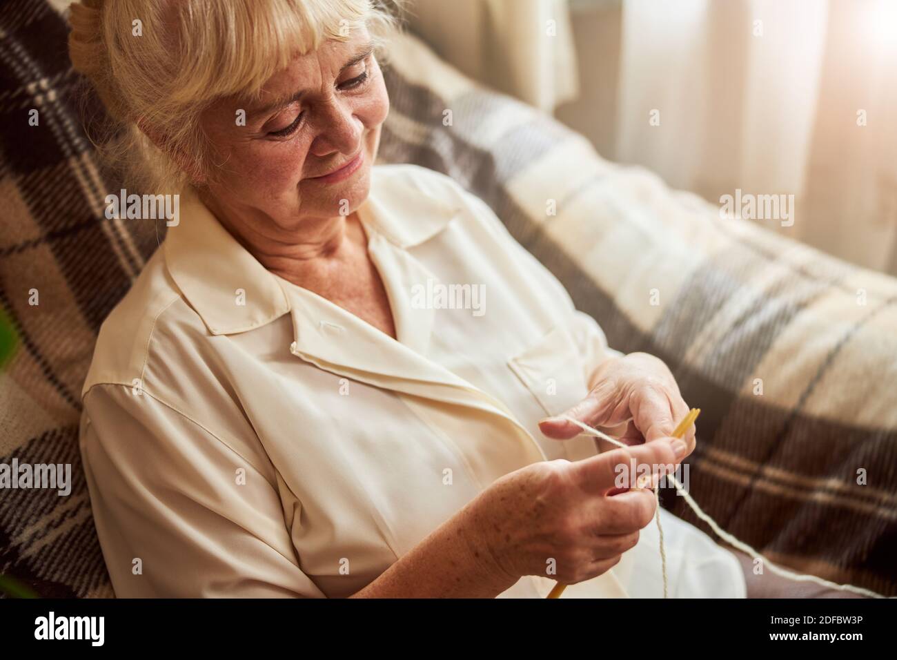 Lovely elderly woman sitting in armchair and knitting Stock Photo - Alamy