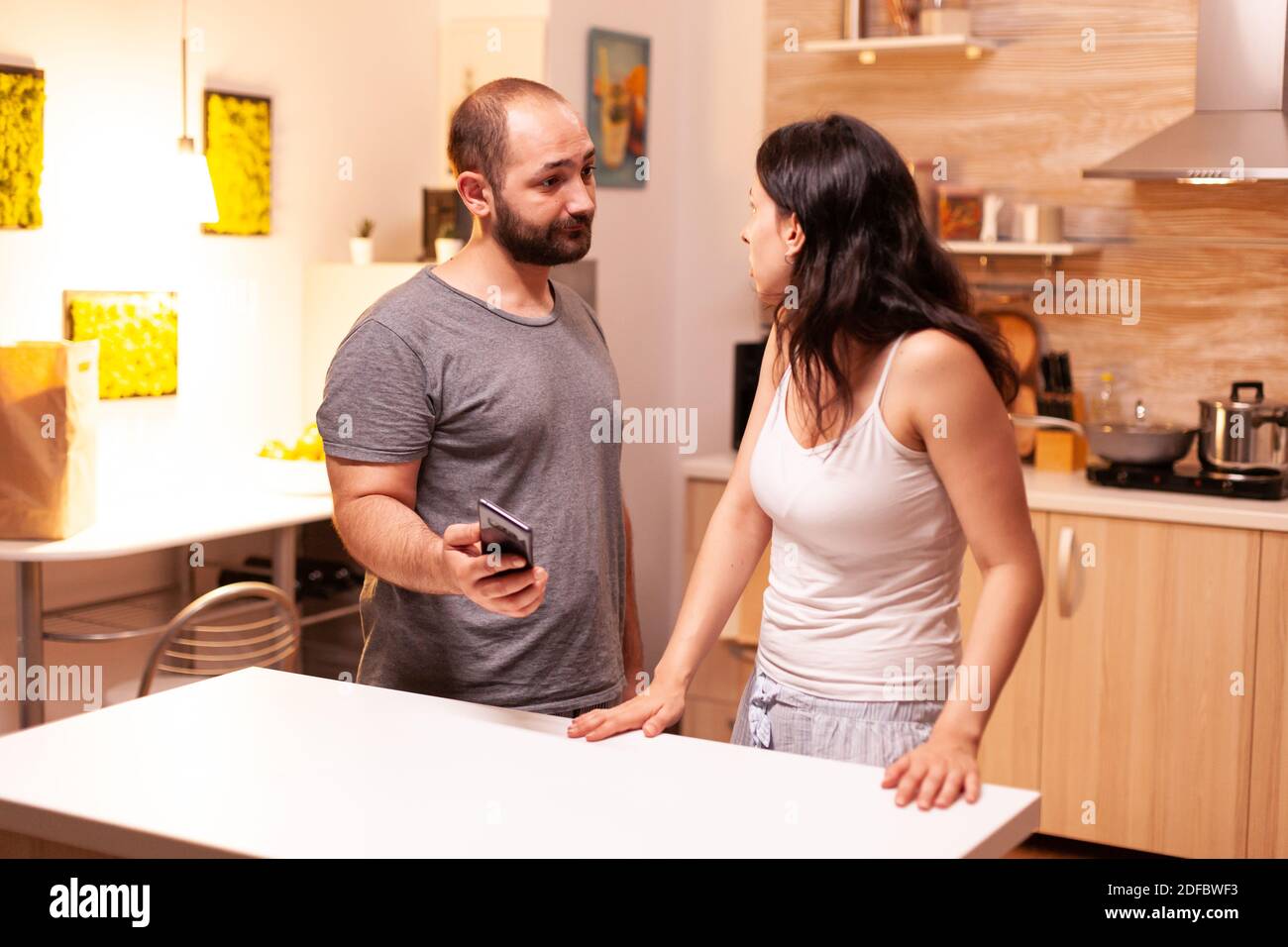 Jealous husband asking for explanations after checking wife's phone. Cheated angry frustrated irritated man accusing woman of infidelity arguing her with messages on smartphone screaming desperate Stock Photo