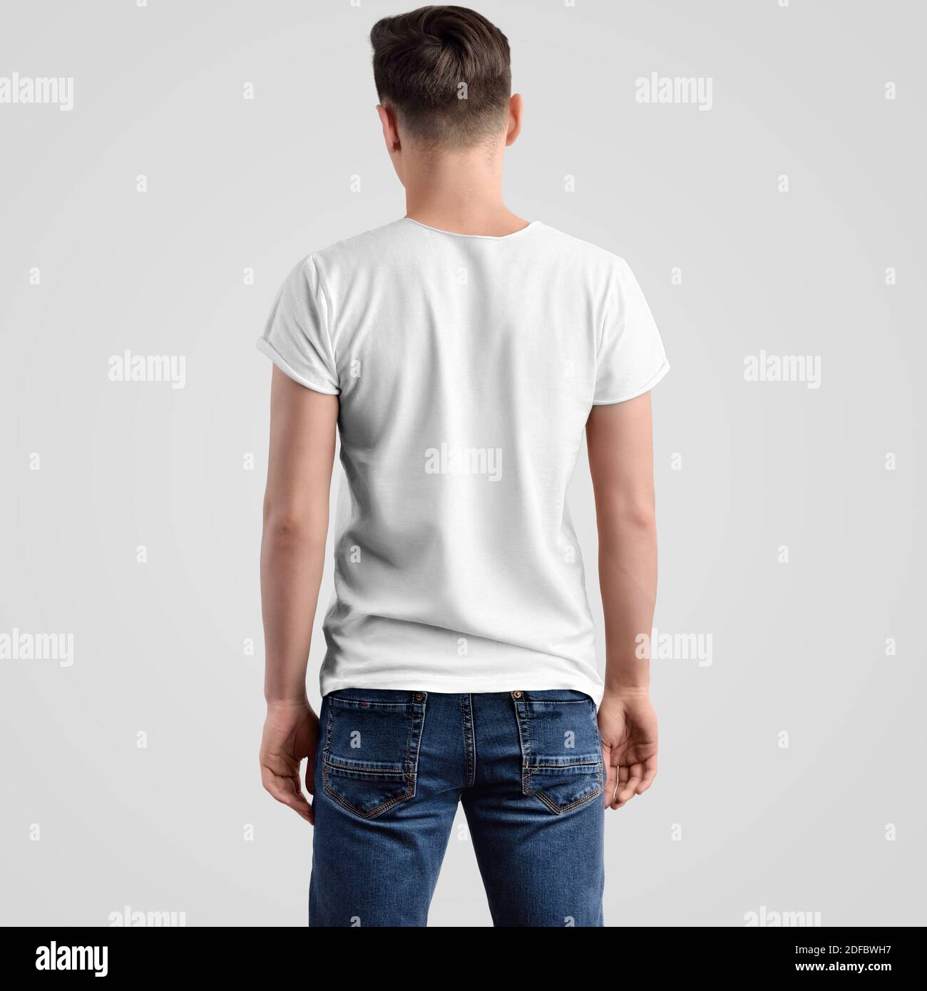 Mockup male t-shirt on a young guy in blue jeans, rear view. Clothing template on white background for design presentation. Stock Photo