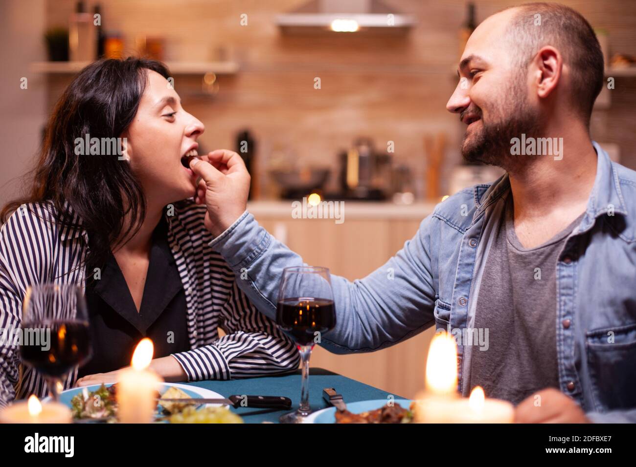 Wife and husband celebrating anniversary with red wine, tender moments