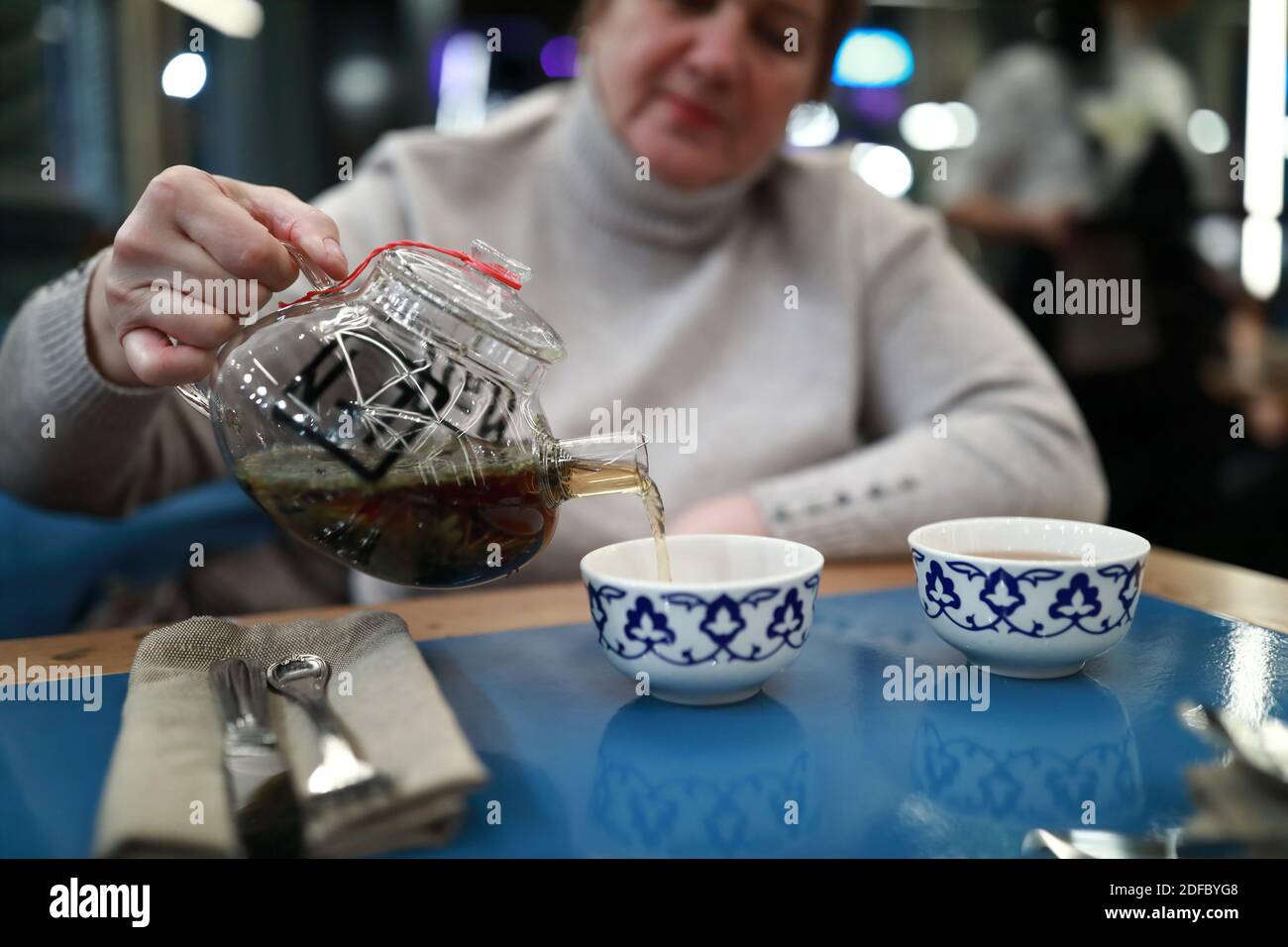 Woman pours tea into cups in restaurant Stock Photo