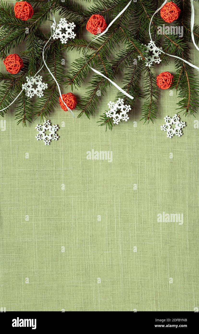 Fir branch, orange rattan balls and white wooden snowflakes on green textile material. Flat lay with natural recyclable decorative elements. Eco frien Stock Photo