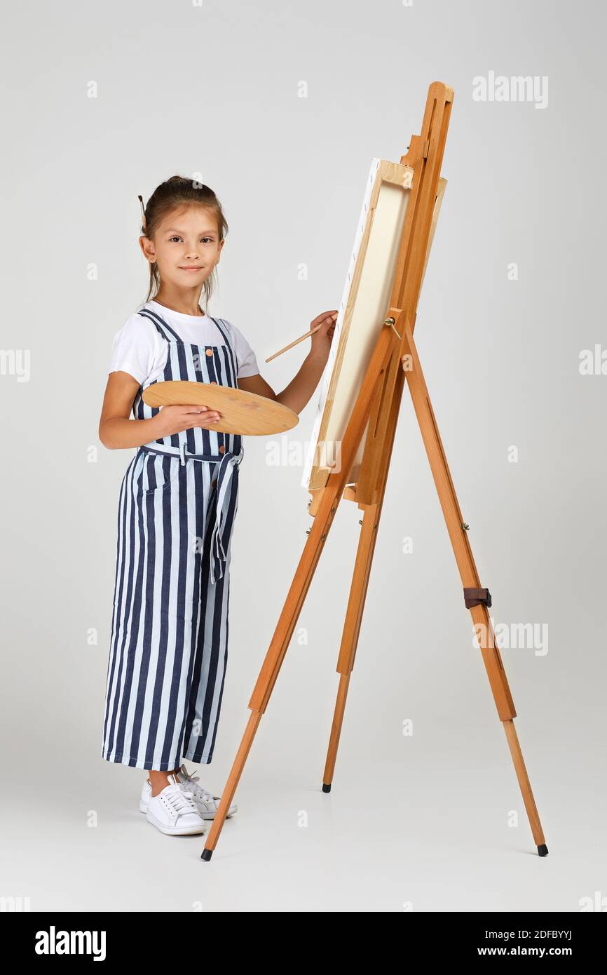 cute little girl holding a wooden art palette and brush on studio ...