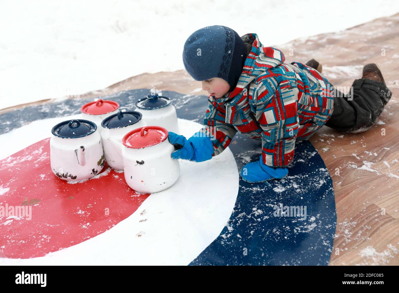 Child playing curling with kettles in winter Stock Photo Alamy