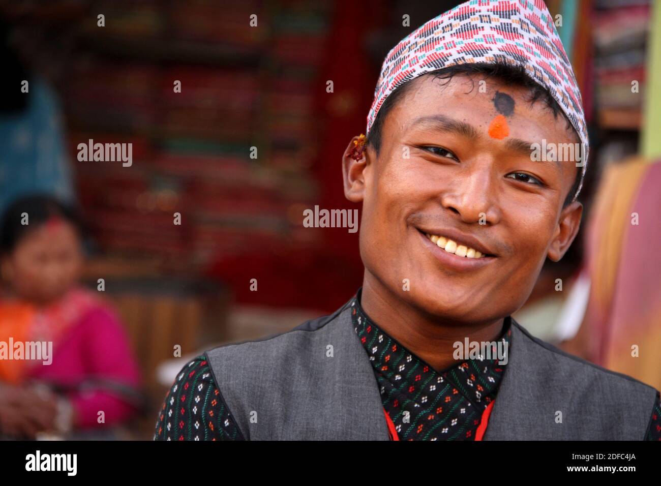 Nepal, in Patan, young Nepalese man smiling with tilak and traditional hat called Dhaka topi Stock Photo
