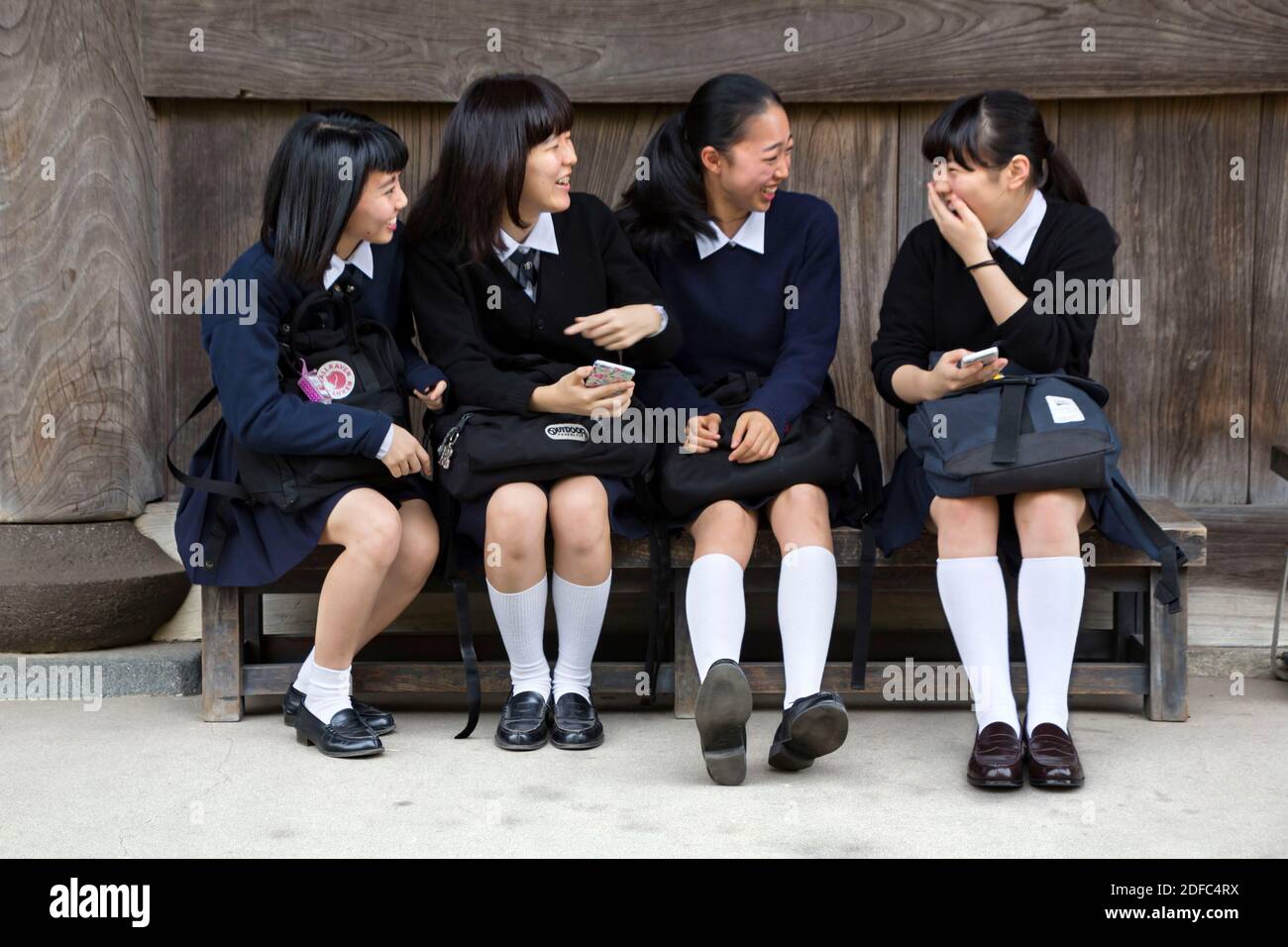 Japan, happy Japanese school girls on a bench in Kamakura Stock Photo