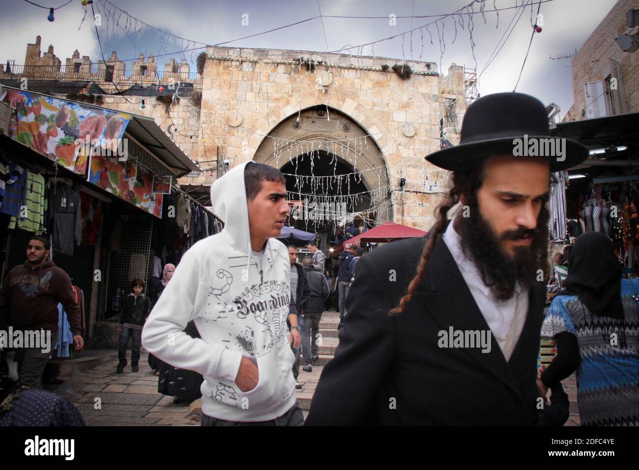 Israel, Jerusalem, Arab man and haredim ultra orthodox Jewish traditional man walk togehter near Damascus gate Stock Photo