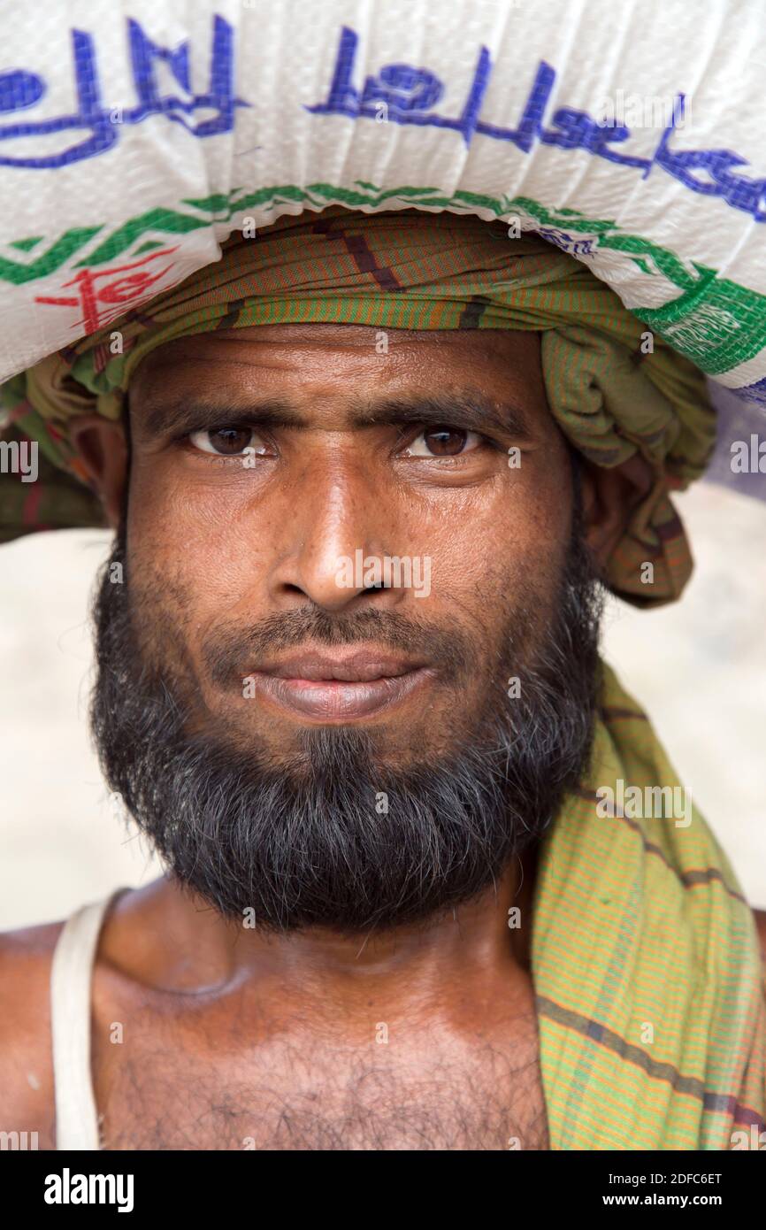 Bangladesh, portrait of hardworking muslim man with beard and turban carrying bag in Dhaka Stock Photo
